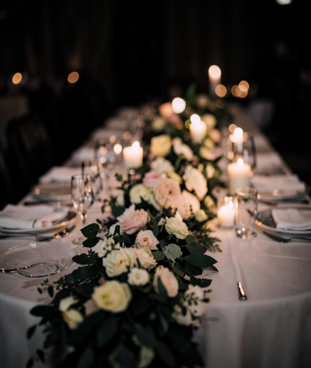 Long wedding table with a floral runner and candlelight